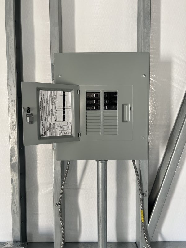 200-AMP-Panel-Box-600×800 Electrical panel box with open door, showcasing circuit breakers and wiring, within a portable storage building context.