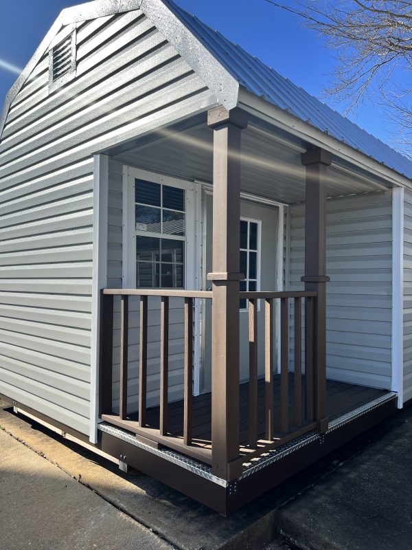 4×8-Corner-Porch-Upgrade-600×800 Portable storage building with a corner porch upgrade, featuring a gray metal exterior, brown railings, and double doors, showcasing customizable design options for sheds by Repo Lot.