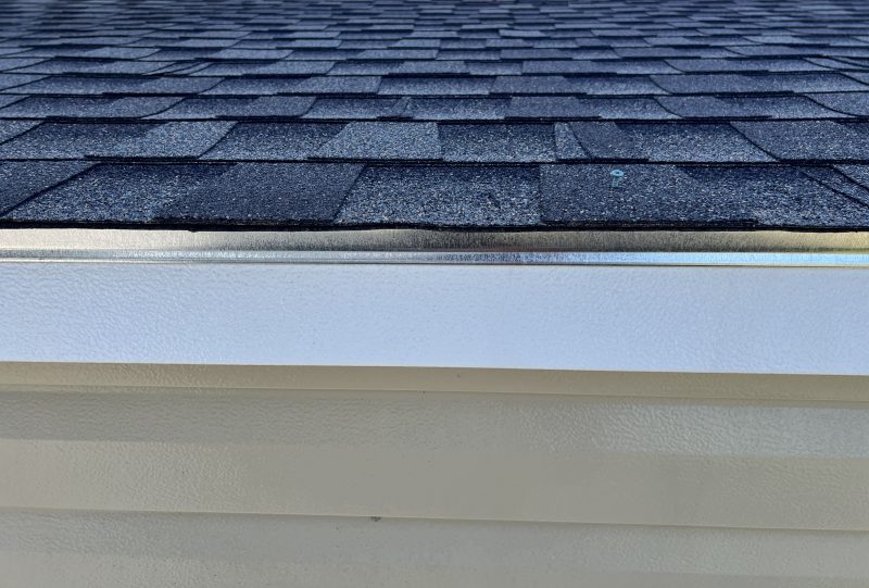 Architectural-Shingles-800×541 Roof detail featuring architectural shingles and white trim, highlighting customization options for portable buildings and sheds.
