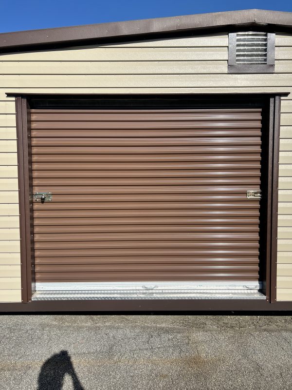 Brown-Rollup-Door-8×7-Wide-Rollup-600×800 Brown roll-up door on a portable storage building with beige siding, showcasing customizable features for storage solutions by Repo Lot.