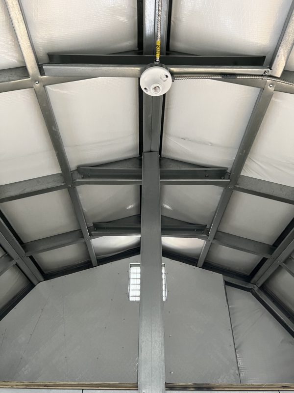 Insulation-for-Lofted-Buildings-600×800 Interior view of a portable storage building showing metal framework, insulation, and ceiling light fixture, highlighting customization options for portable buildings at Repo Lot.