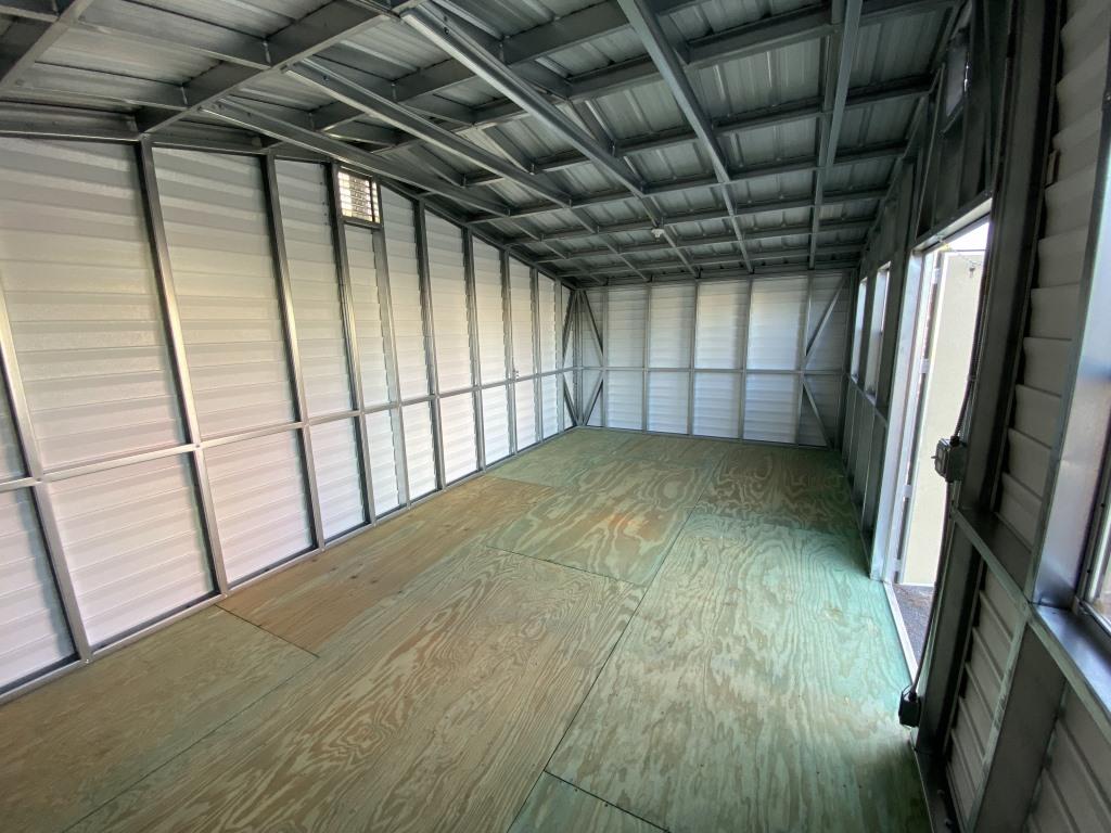 Interior view of a side-gable portable cabin with plywood flooring and metal walls, showcasing a functional space suitable for storage or various uses.