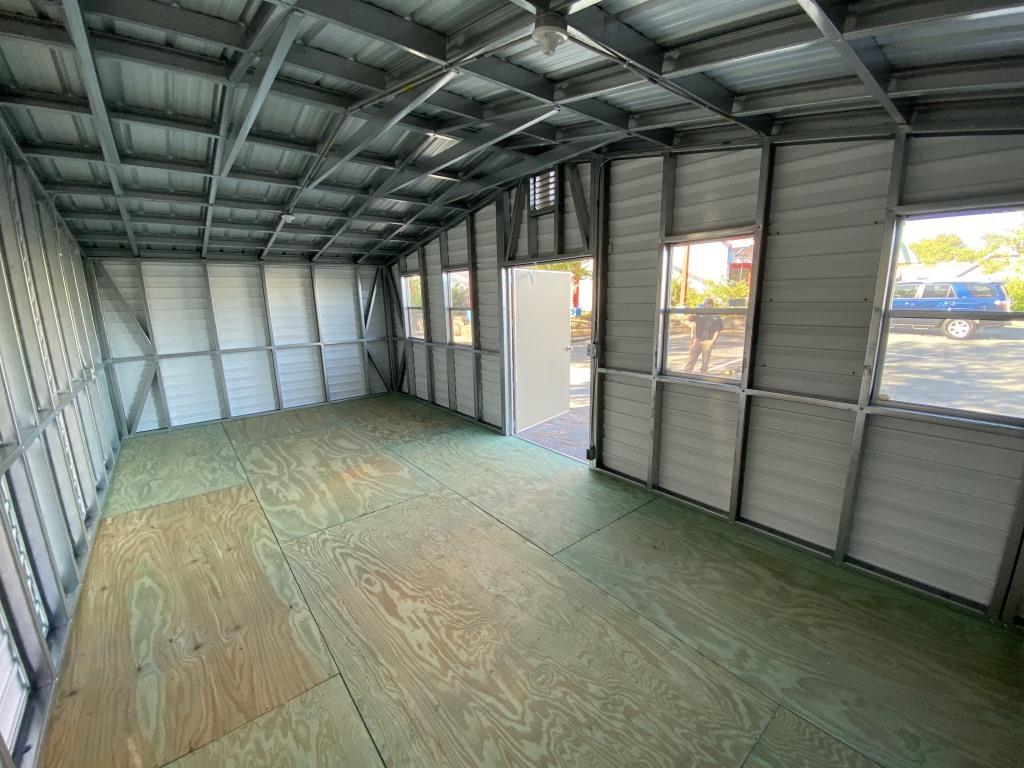 Interior view of a side-gable portable cabin with a wooden floor, metal framing, and windows, showcasing functional space suitable for storage, office, or workshop use.