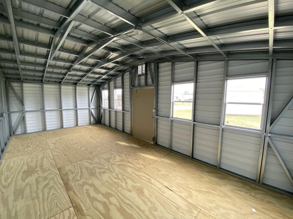 Interior view of a side-gable portable cabin featuring a spacious wooden floor, metal framing, and multiple windows for natural light, highlighting its potential as a versatile workspace or storage solution.