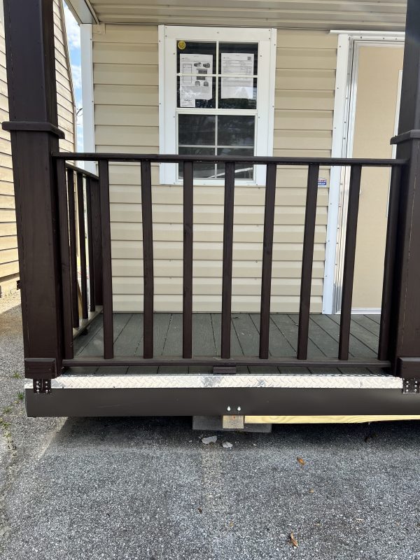 Railing-600×800 Portable storage building entrance with brown railing, wooden deck, and window showcasing customization options.