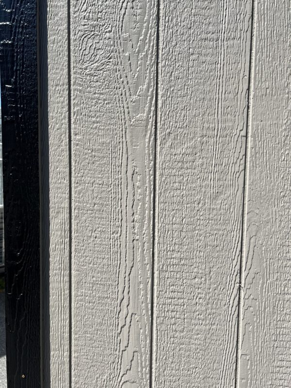 Smart-Board-Siding-600×800 Textured smart board siding in light gray with a black trim, showcasing customizable options for portable buildings and sheds.